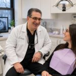 Dr. John Como consulting with a patient in a modern dental treatment room, reviewing digital imaging and discussing personalized dental care in a state-of-the-art New Rochelle practice.